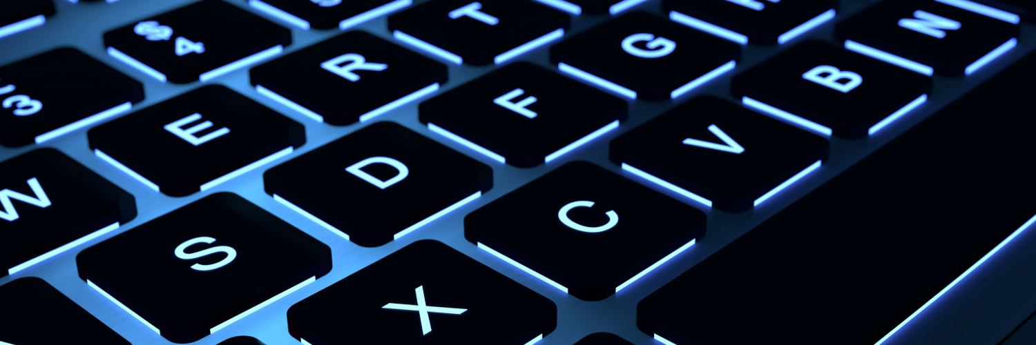 Close up of a black laptop keyboard where keys are backlit and outlined with blue light