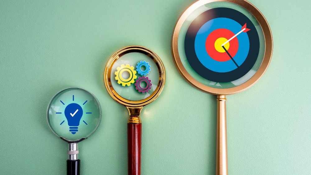 Three magnifying glasses pointing at a lightbulb, cogs, and a bullseye