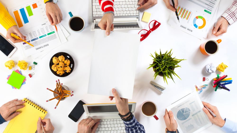 A board of trustees sat around a table, using laptops and printed resources