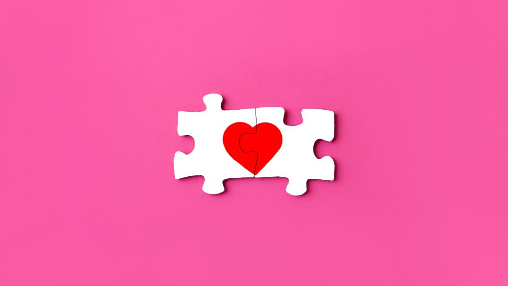 Two puzzle pieces fitting together, making up a heart