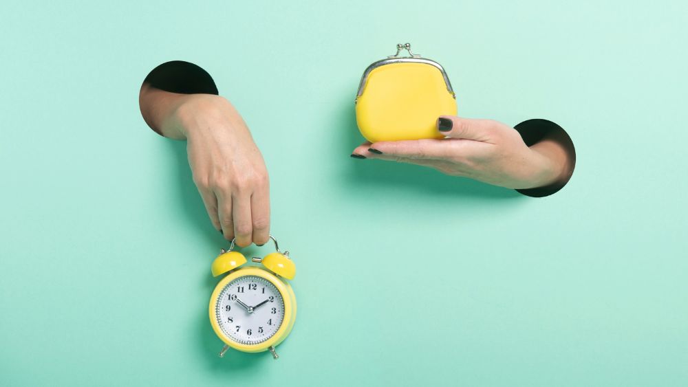 Hands hold an alarm clock and a coin purse, representing resources