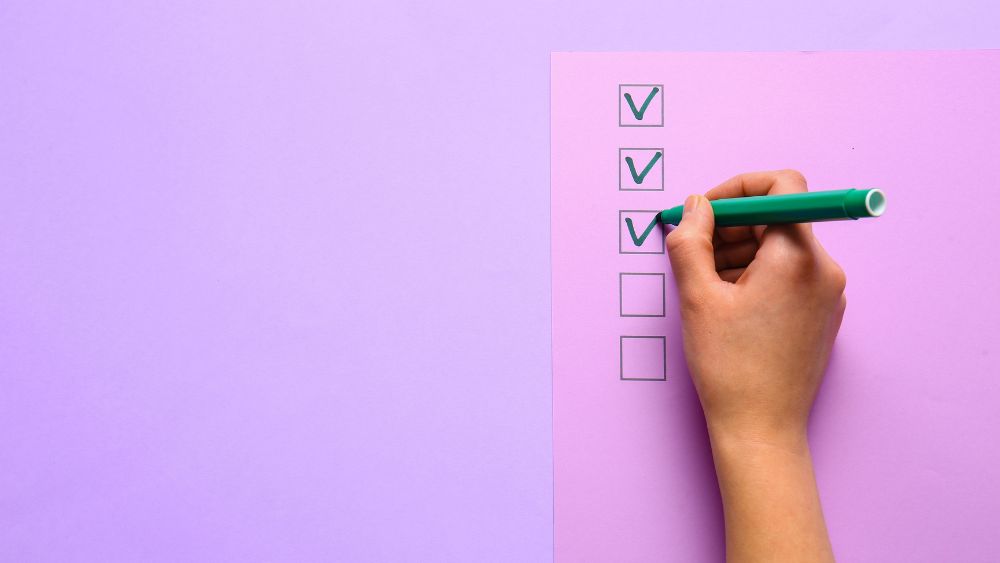 A person filling out a pink and purple checklist, representing criteria for new AI tools
